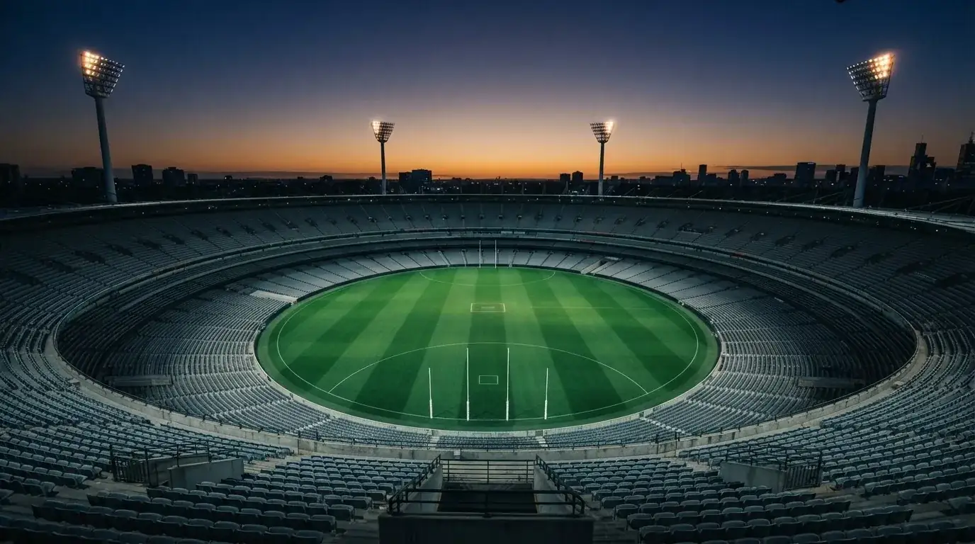 An empty football stadium with floodlight masts at dusk