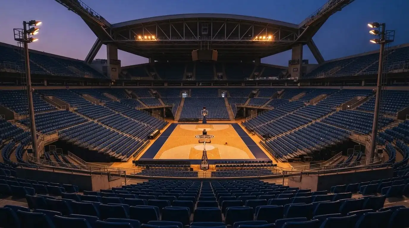 An empty football stadium with floodlight masts at dusk