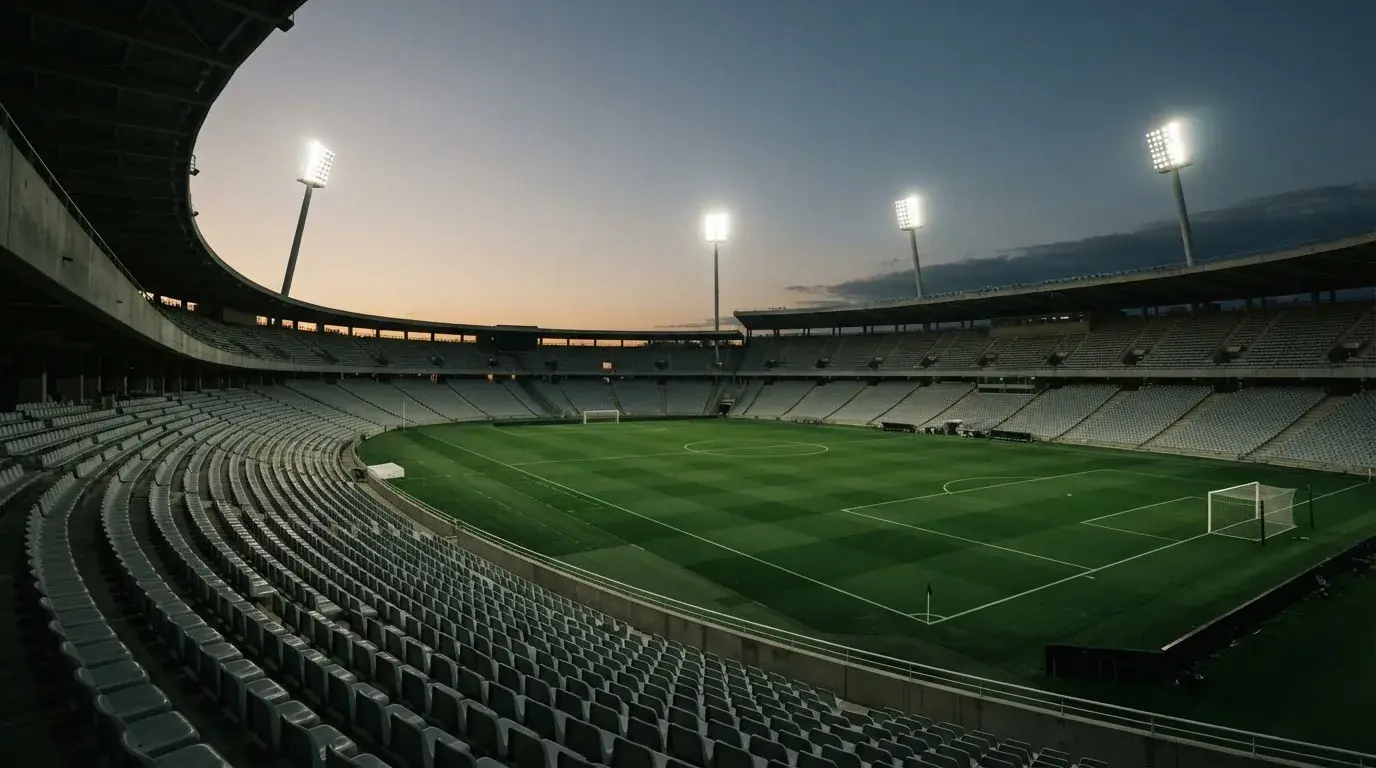 An empty football stadium with floodlight masts at dusk