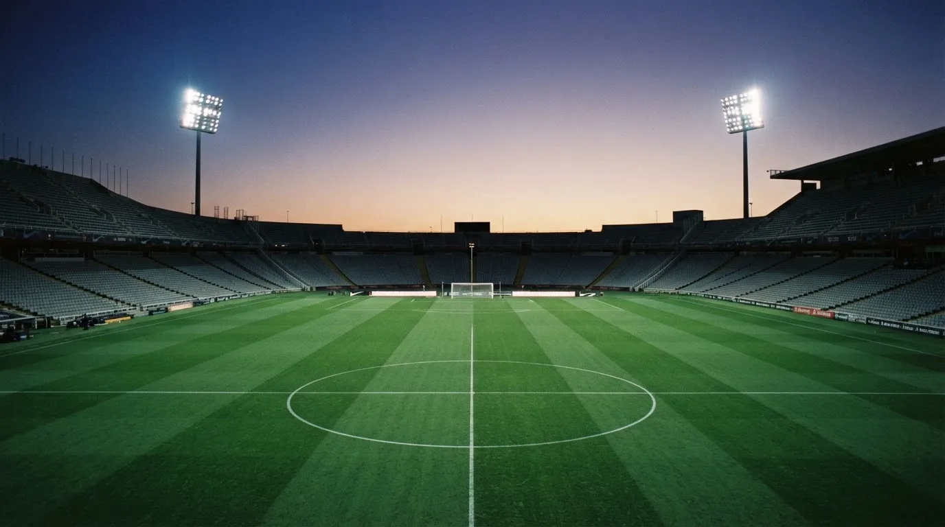 An empty football stadium with floodlight masts at dusk