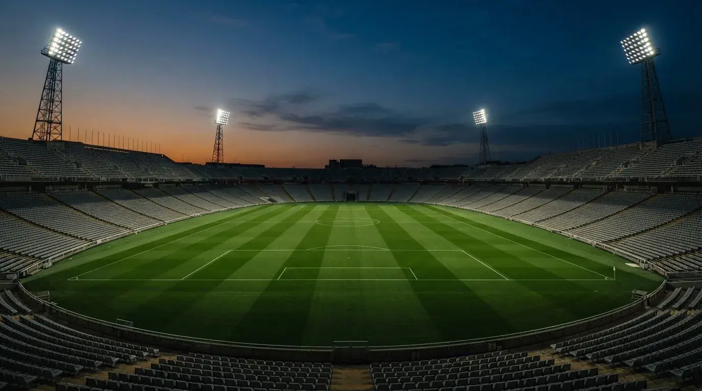 An empty football stadium with floodlight masts at dusk