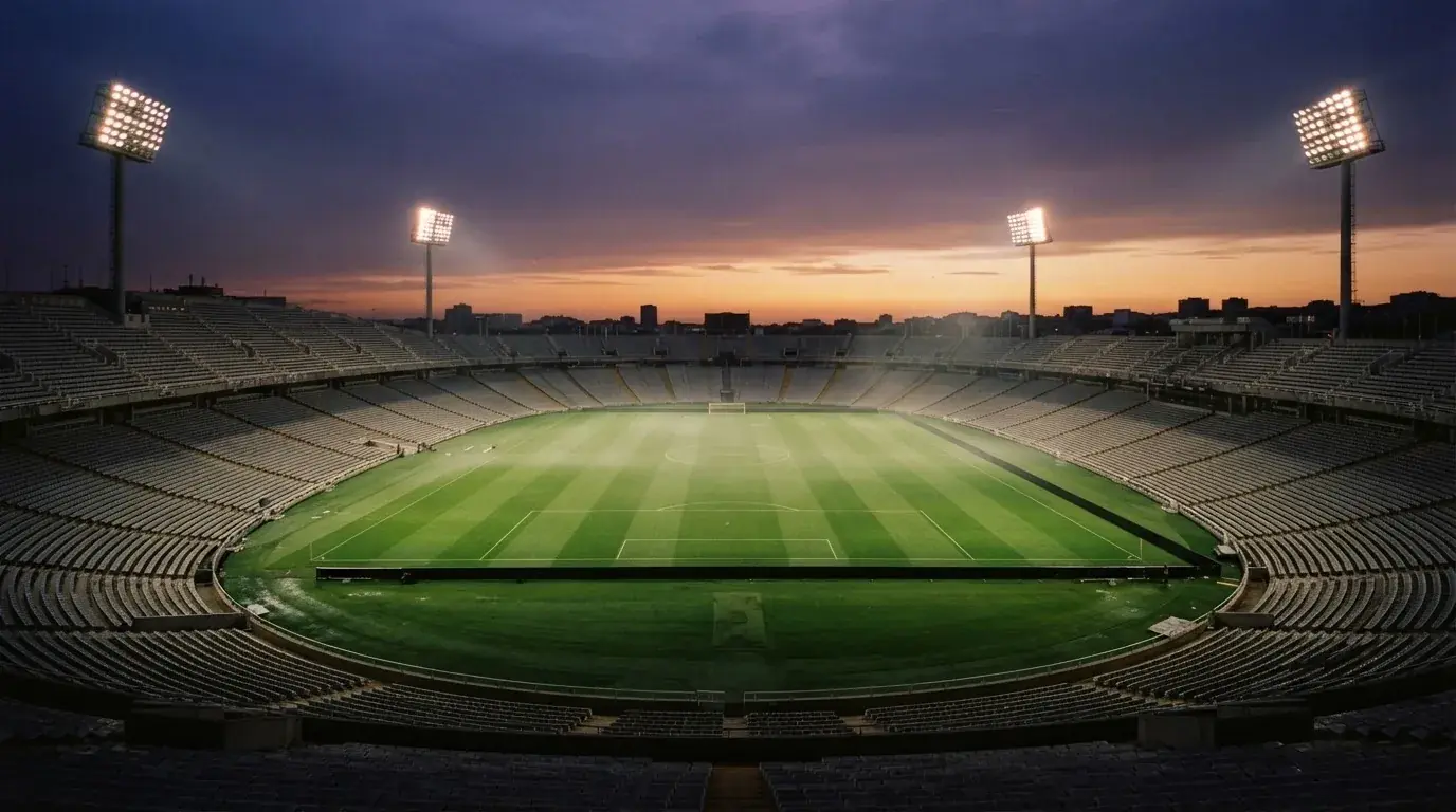 An empty football stadium with floodlight masts at dusk
