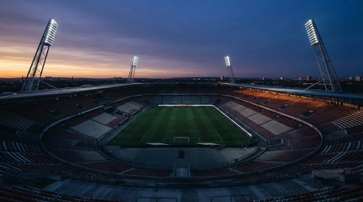 An empty football stadium with floodlight masts at dusk