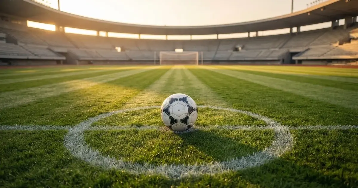 A ball on the centre spot of a grass pitch in morning light