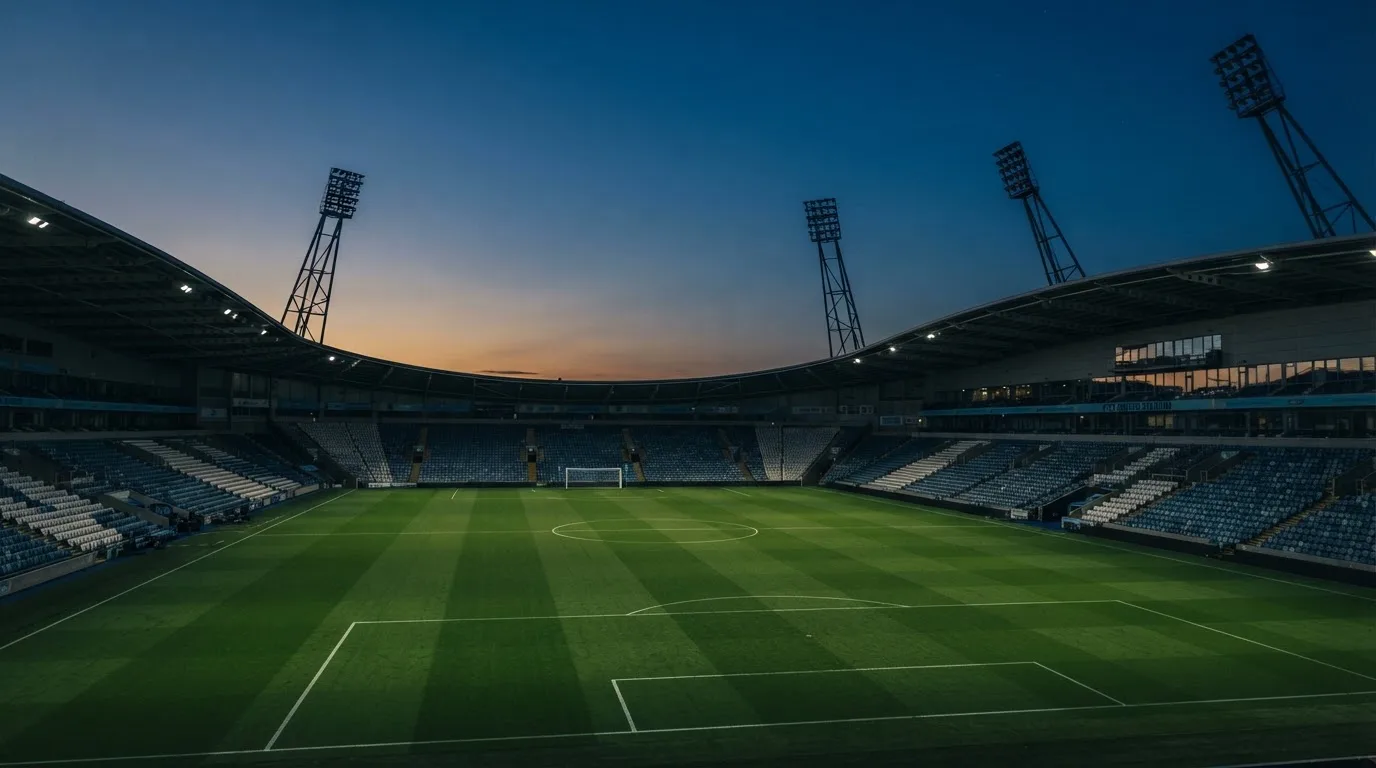 An empty football stadium with floodlight masts at dusk