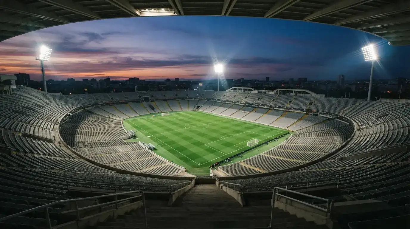 An empty football stadium with floodlight masts at dusk
