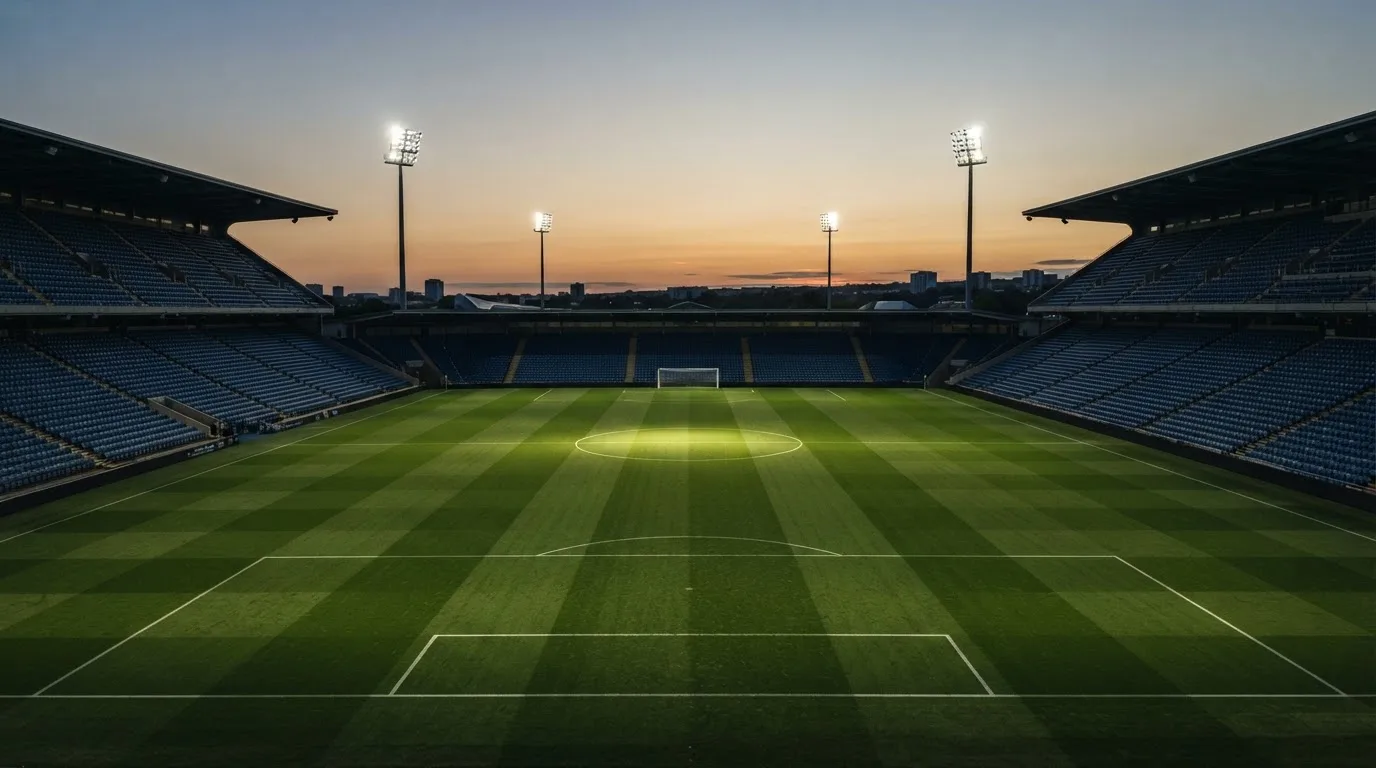 An empty football stadium with floodlight masts at dusk