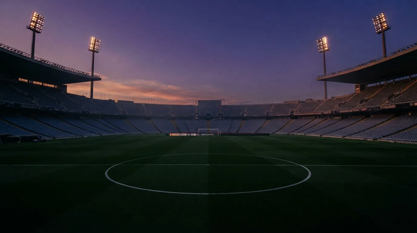 An empty football stadium with floodlight masts at dusk