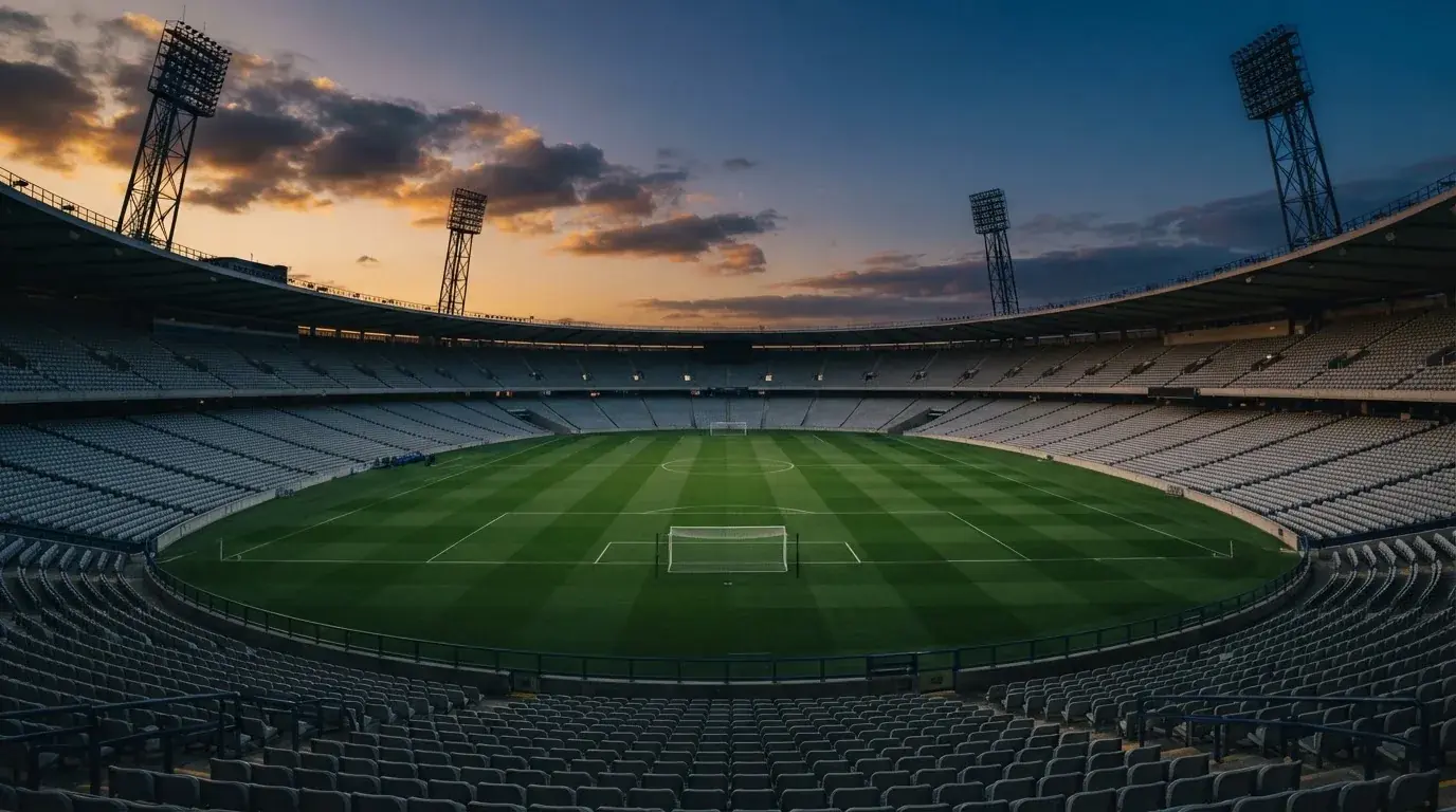 An empty football stadium with floodlight masts at dusk