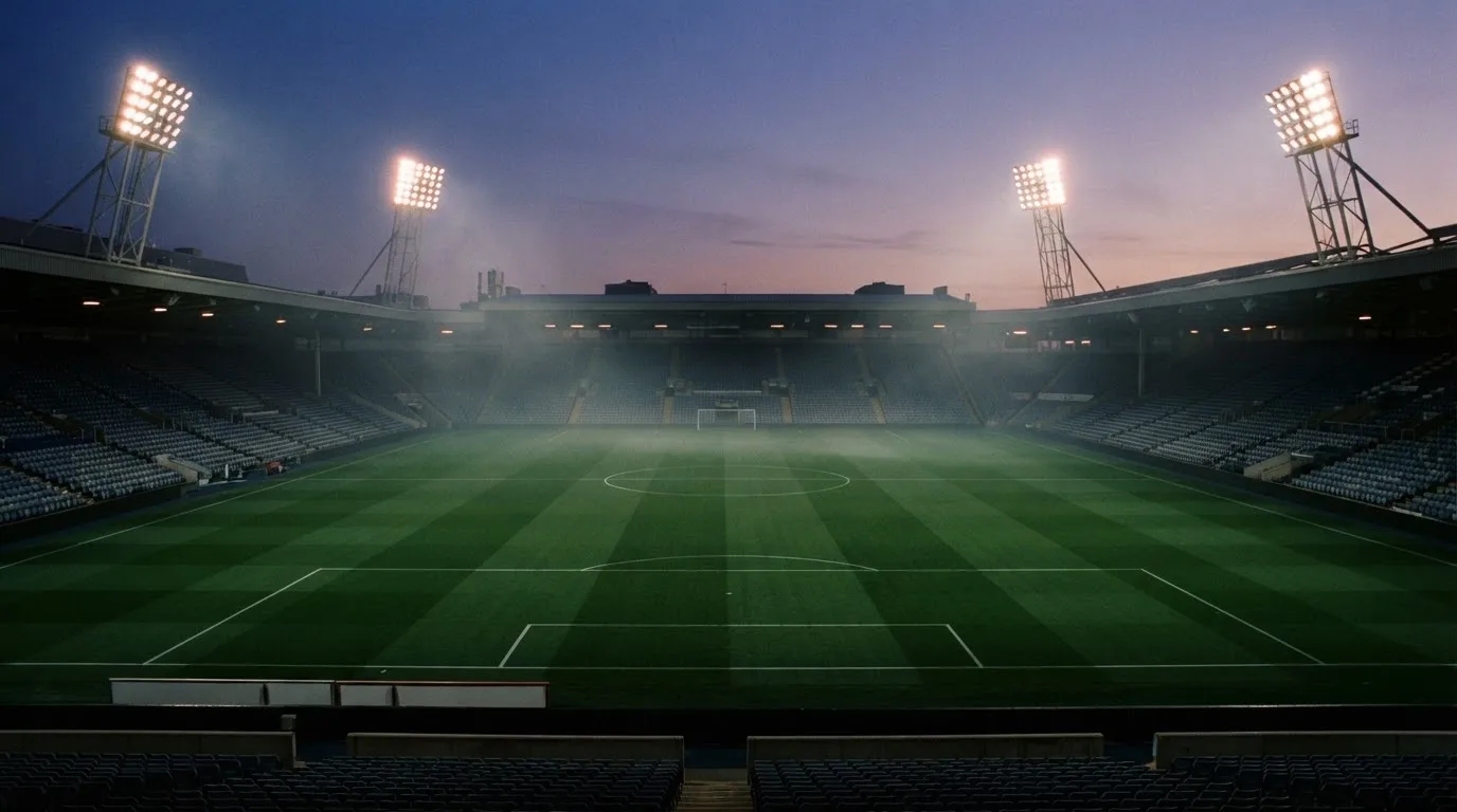 An empty football stadium with floodlight masts at dusk