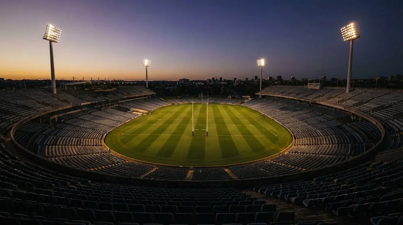 An empty football stadium with floodlight masts at dusk