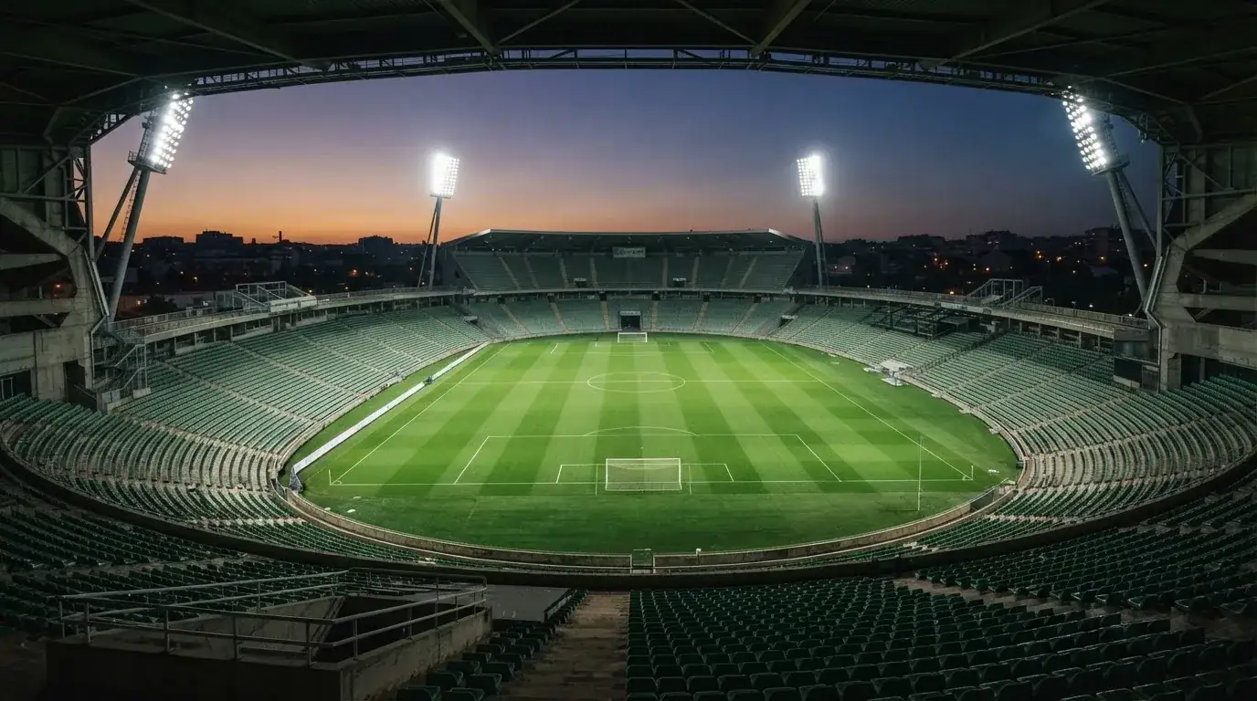 An empty football stadium with floodlight masts at dusk