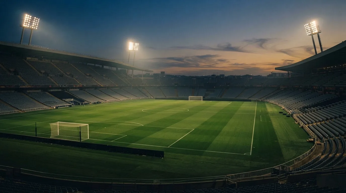 An empty football stadium with floodlight masts at dusk