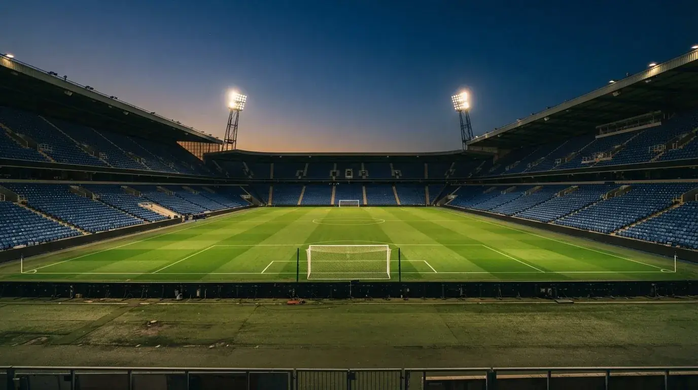 An empty football stadium with floodlight masts at dusk